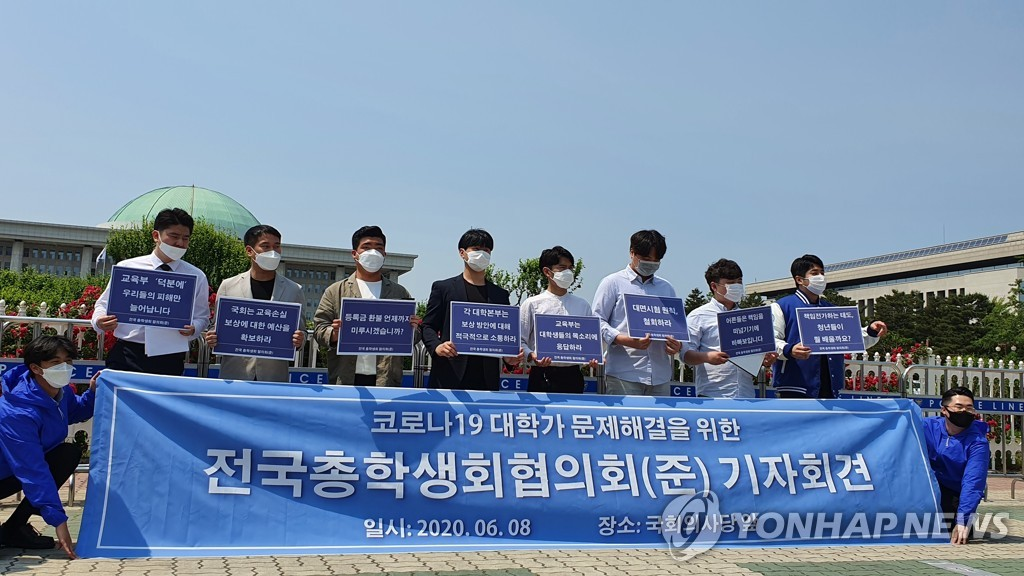 韓國學生在國會外抗議要求學費退款，手持標語和藍色橫幅。