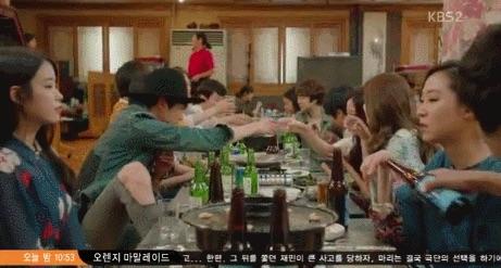 กลุ่มคนเกาหลีนั่งโต๊ะในร้านอาหาร กำลังยกแก้วเครื่องดื่มเพื่อชนกัน สะท้อนวิถีชีวิตการสังสรรค์ของชาวเกาหลี