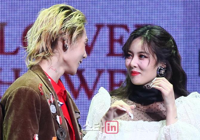 ヒョナとDAWNが舞台上で親しげに話しているシーン。ヒョナは白いドレスを着ている。カップルイベントでの公式な場面です。