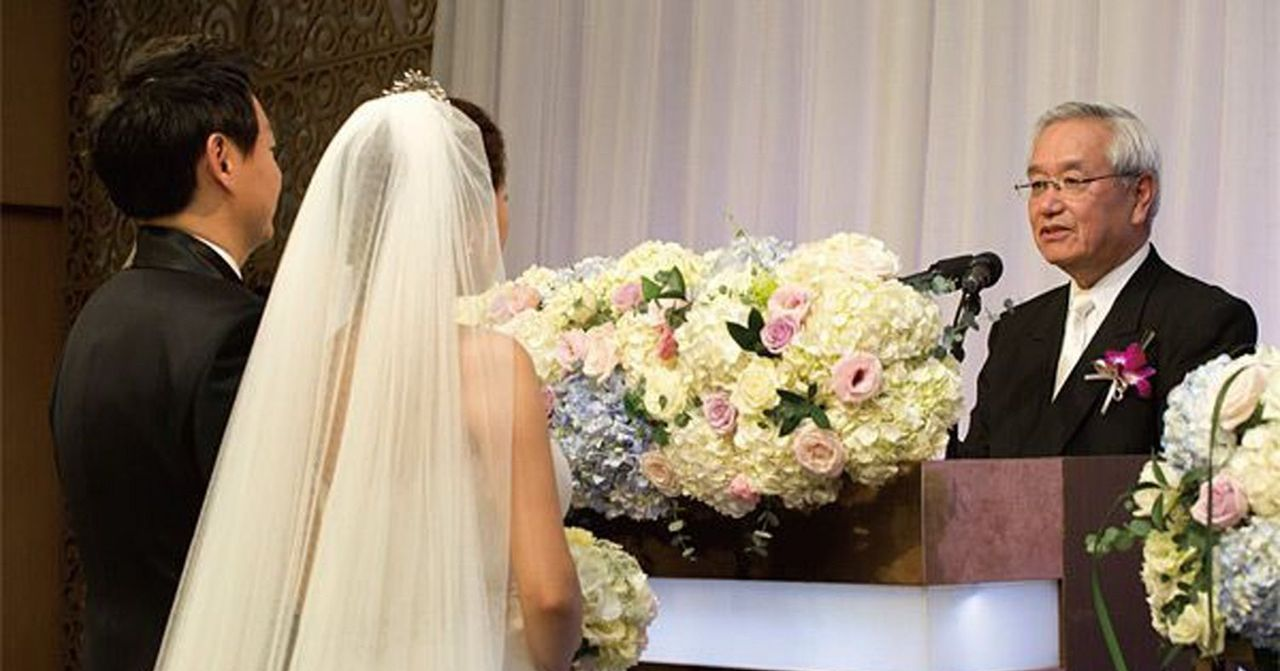 新娘和新郎在婚禮上面對著講台，場景被美麗的花藝裝飾，展現韓國婚禮的典雅與浪漫風格。