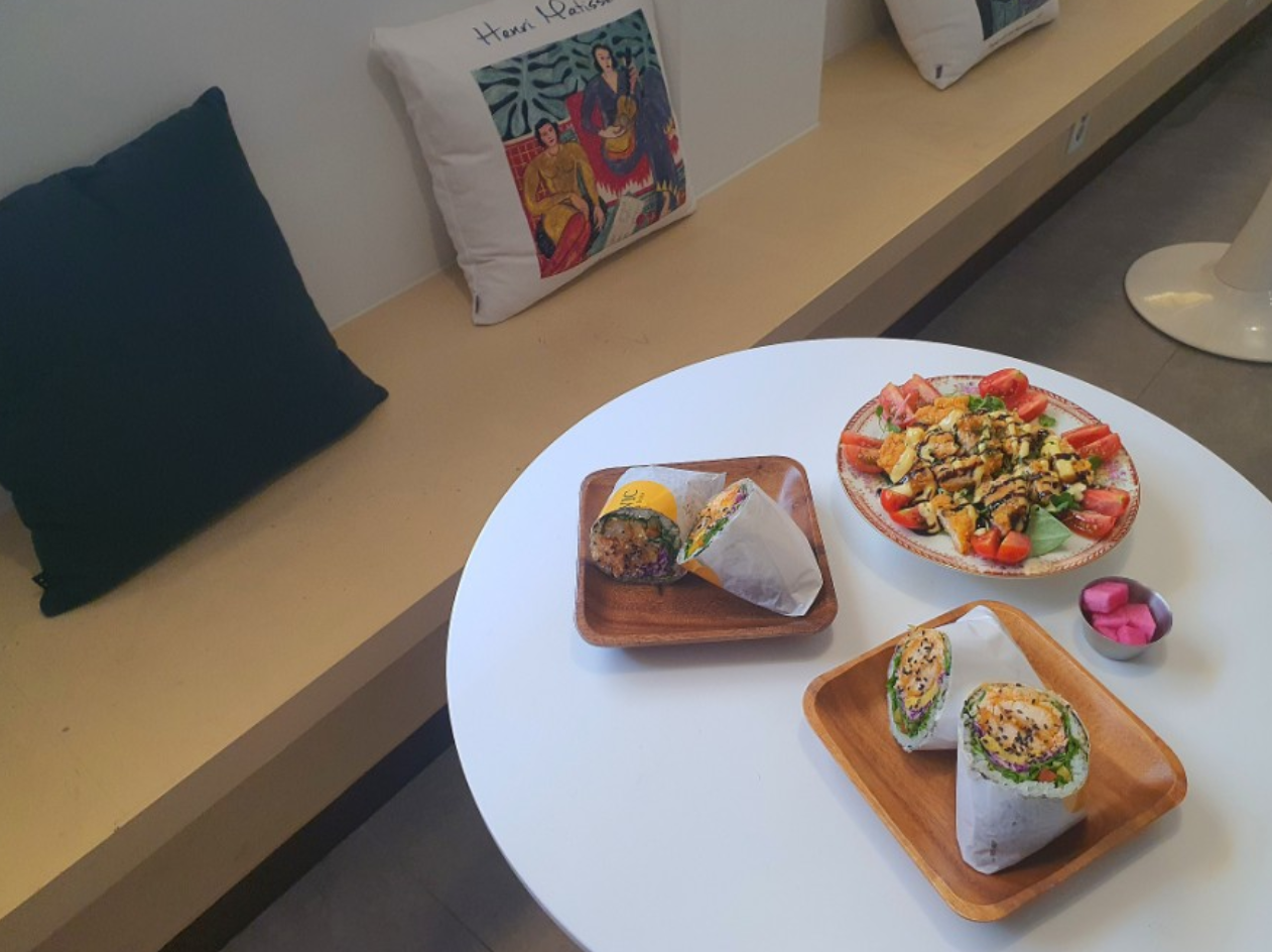 Lowicカフェのダイニングエリアに並べられたブリトーとサラダ、韓国料理の新しいバリエーションとしてカラフルで魅力的。