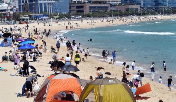 釜山海雲台海水浴場 2023年夏、多くの人々が青い海を眺めながらリラックスしている様子。海岸にはカラフルなテントやパラソルが広がっている。韓国の夏の風景