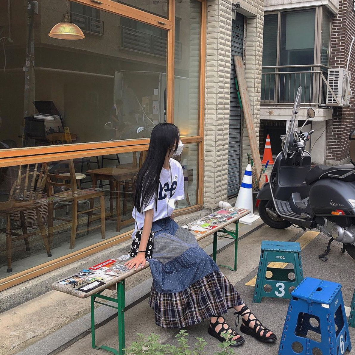 长裙和T恤搭配的休闲风格服饰,结合黑色罗马鞋,适合在街边或咖啡馆休闲时穿着。