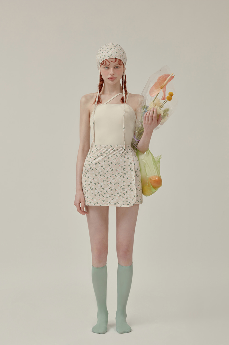 淡色吊帶式泳裝搭配印花短裙和花藝背景