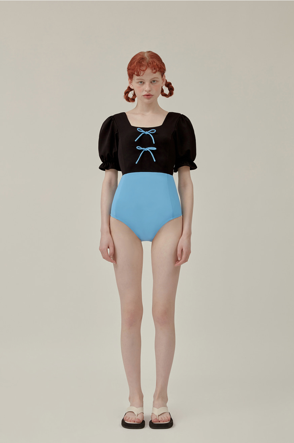 穿著黑色上衣和藍色高腰泳裝的模特兒