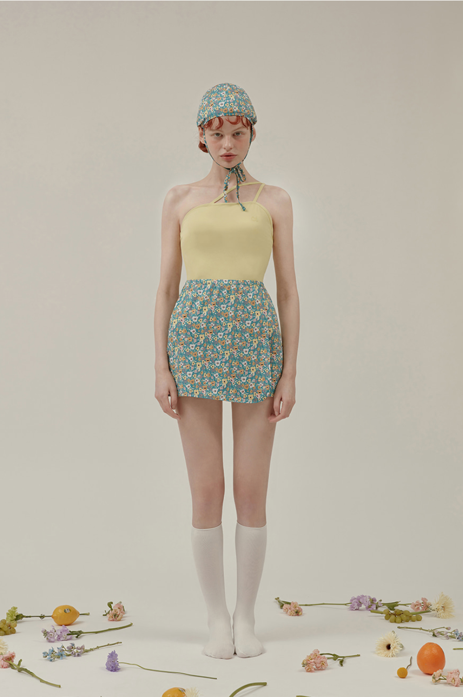 黃色上衣搭配藍色花卉裙的泳裝設計，周圍有花卉裝飾
