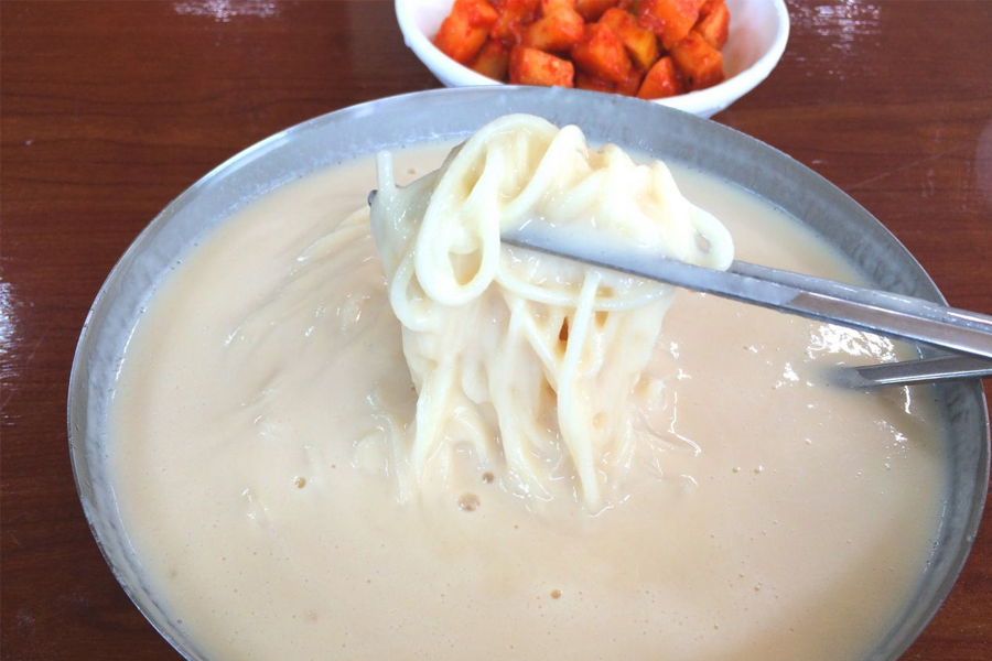 甜味型韓國豆漿冷麵，淋上白砂糖，麵條淹沒在豆漿中，令人驚訝的韓國夏天甜食。