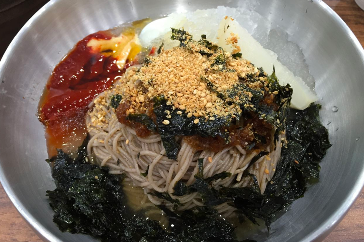 一碗蕎麥麵混合泡菜汁、海苔、辣醬和碎堅果，料理色彩豐富，是韓式夏天必嘗美食。