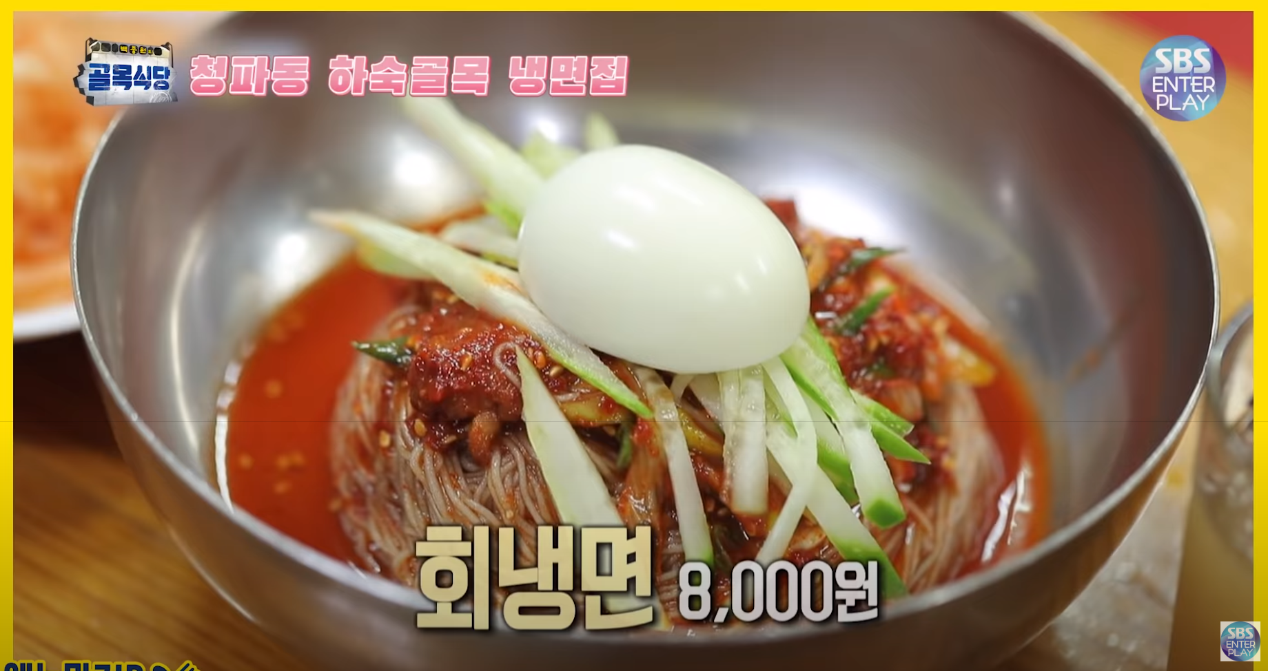 オボクハムン冷麺の人気メニュー、辛冷麺が金属の器に盛られている画像。緑のキュウリと半分に切った玉子がのっており、価格は8000ウォンと表示されている。