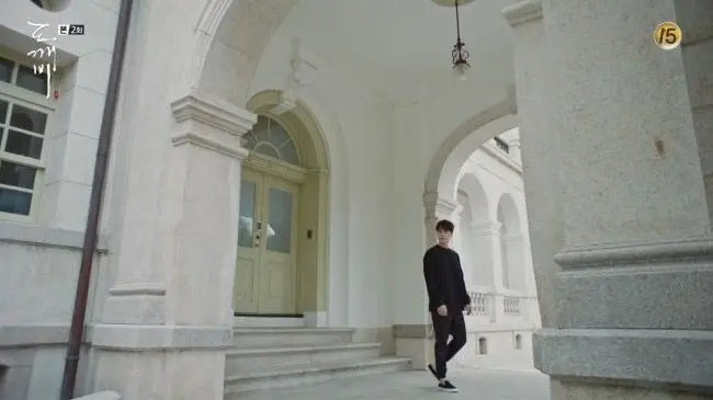 Character standing near a white archway at Yunhyeongung Western House, Goblin filming location.