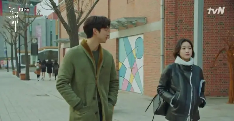 Goblin drama scene with characters walking near a brick building, Incheon Art Platform location.