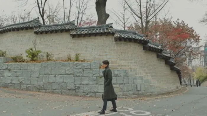 Character walking along the stone wall of Deoksugung Stonewall Walkway, Goblin filming location.