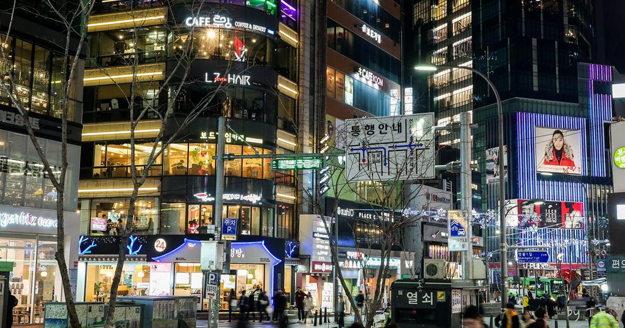 ภาพของย่านชินชนเกาหลีตอนกลางคืน แสดงถึงอาคารร้านค้าสูงหลากหลายระดับ พร้อมด้วยไฟประดับระยิบระยับตามถนน