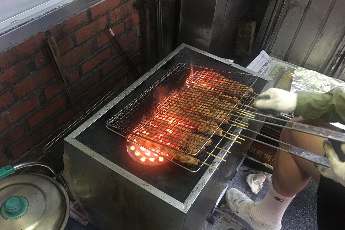 韓國燒烤雞肉串在湖水家餐廳前炭火上燒烤，展示出美味的燒烤進行中的過程。