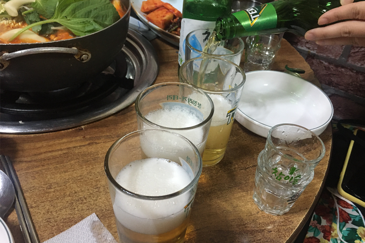 在首爾湖水家，將燒酒倒入杯中準備享用，這是體驗韓國飲食文化的必備步驟。