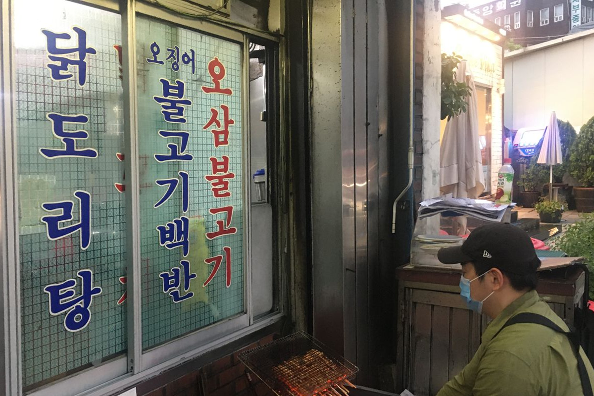 湖水家餐廳前的員工正在燒烤雞肉串，使用的是傳統的炭火，展現出韓國炭烤的古早味魅力。