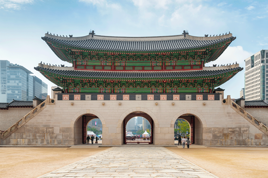 The grand Gwanghwamun Gate of Gyeongbokgung Palace, a historic site in Seoul with its colorful traditional architecture against a modern city backdrop.