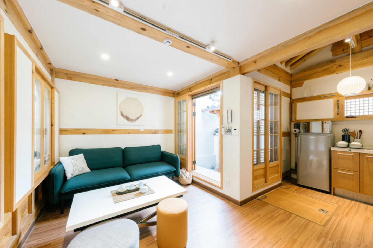 木の梁が見える明るくモダンなリビングルーム、韓屋スタイルのアダムハノクのリビングスペース