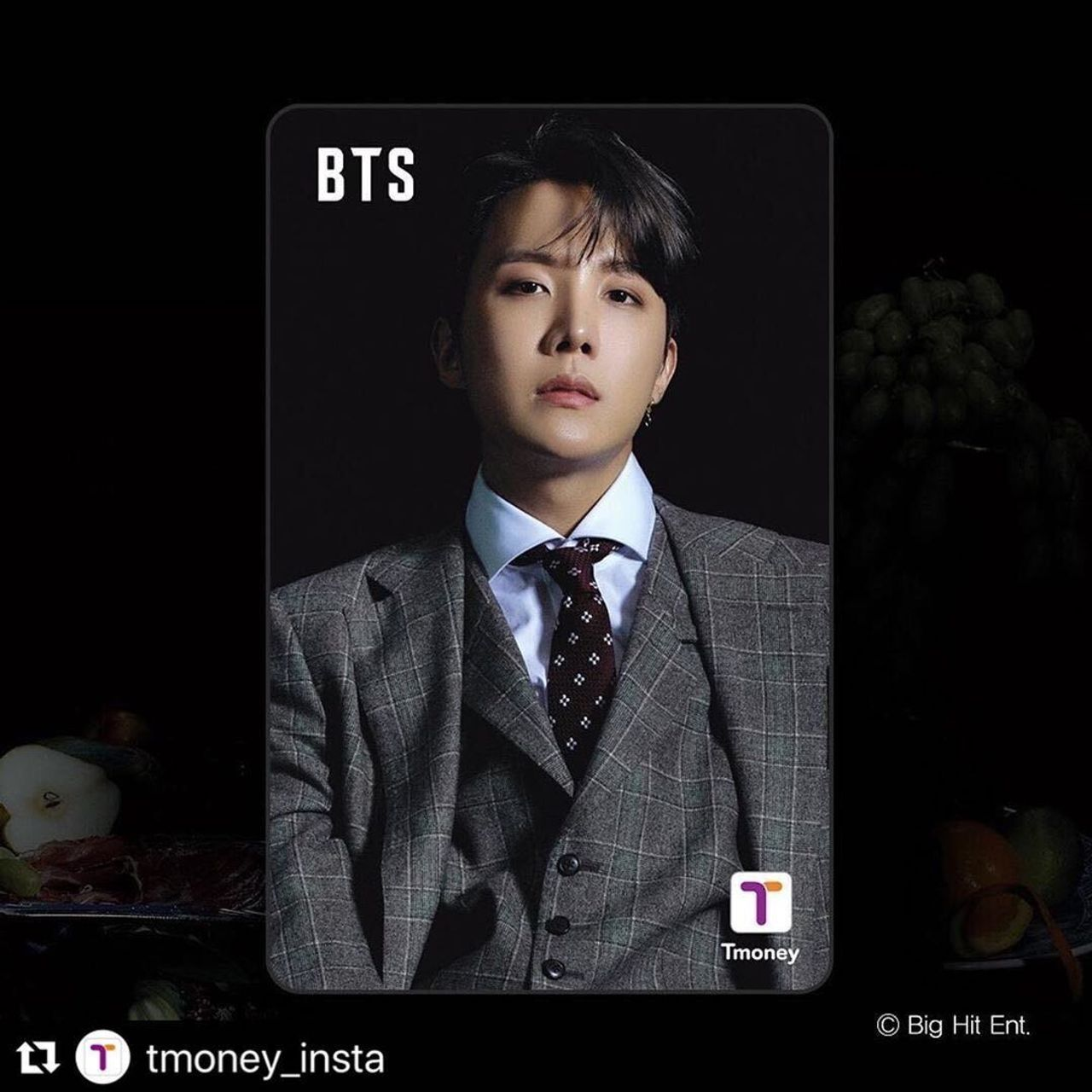 綠色西裝的BTS成員展示T-money交通卡，背景擺放著精美的水果和餐具
