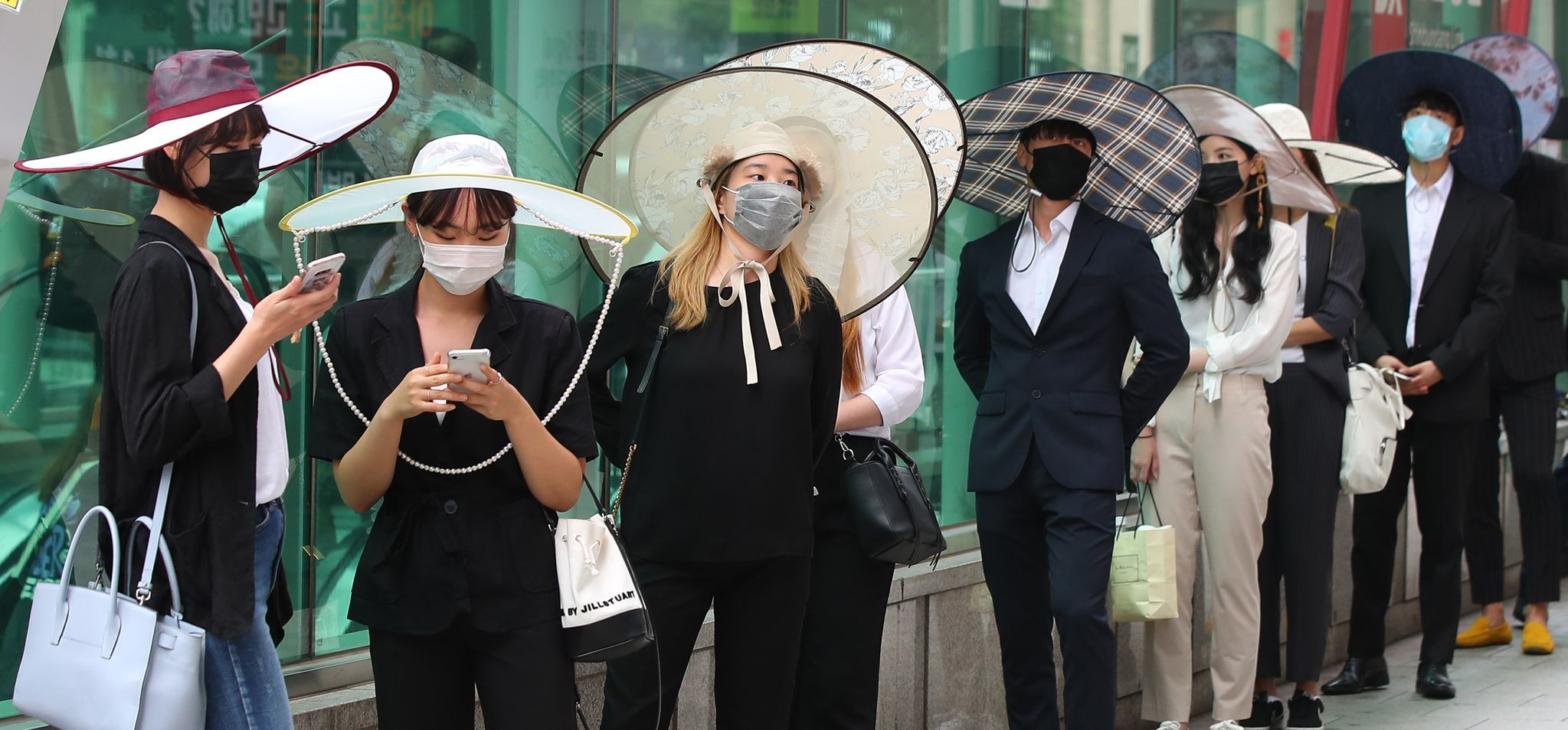 人们在首尔江南站佩戴韩国社会距离帽（K-God），此帽子灵感来自韩国传统书生帽，增强个人之间的社交距离。