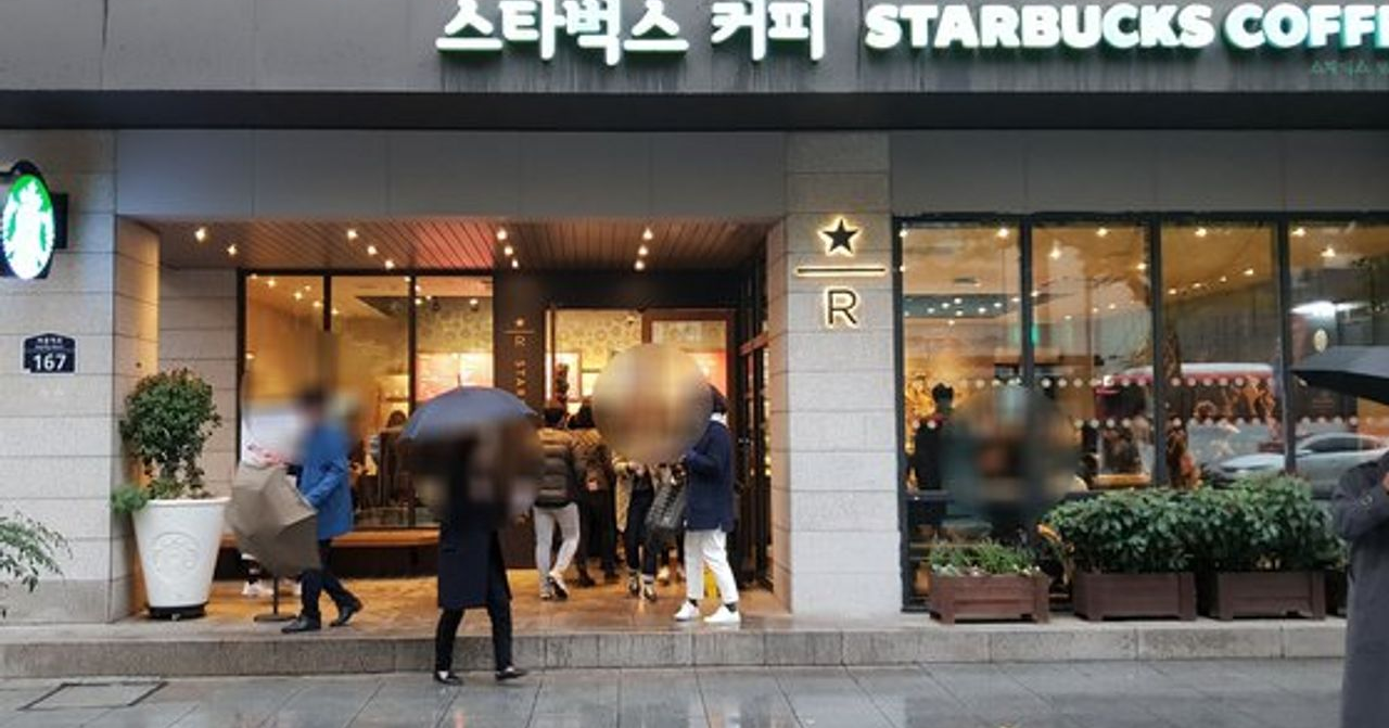 位于韩国的一家星巴克门店，顾客在门口排队等待进入，展示星巴克成功的原因之一是其高人气。