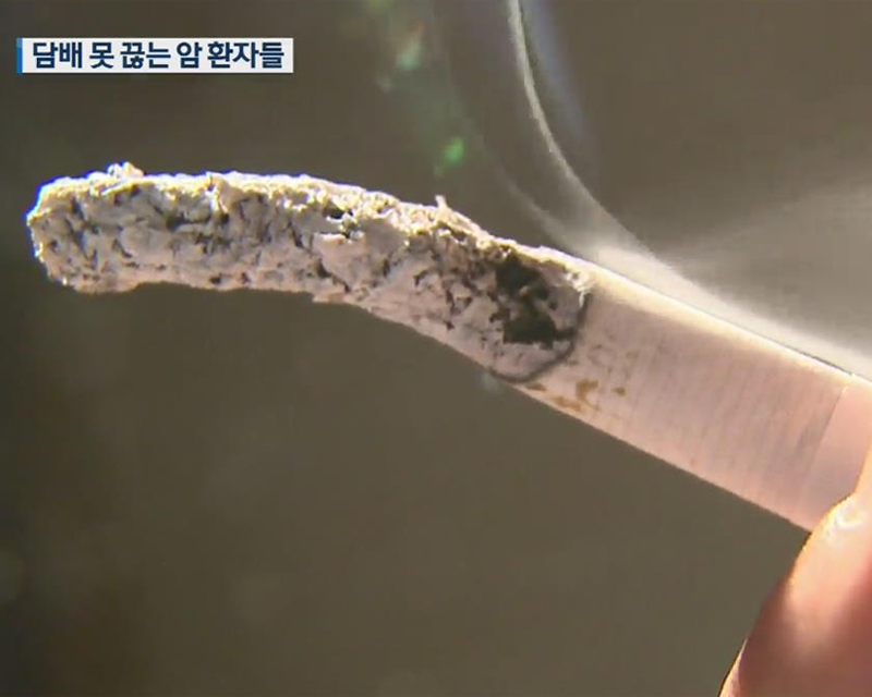 一支正在燃燒的香煙，煙頭有長長的灰，強調吸煙對健康的影響。