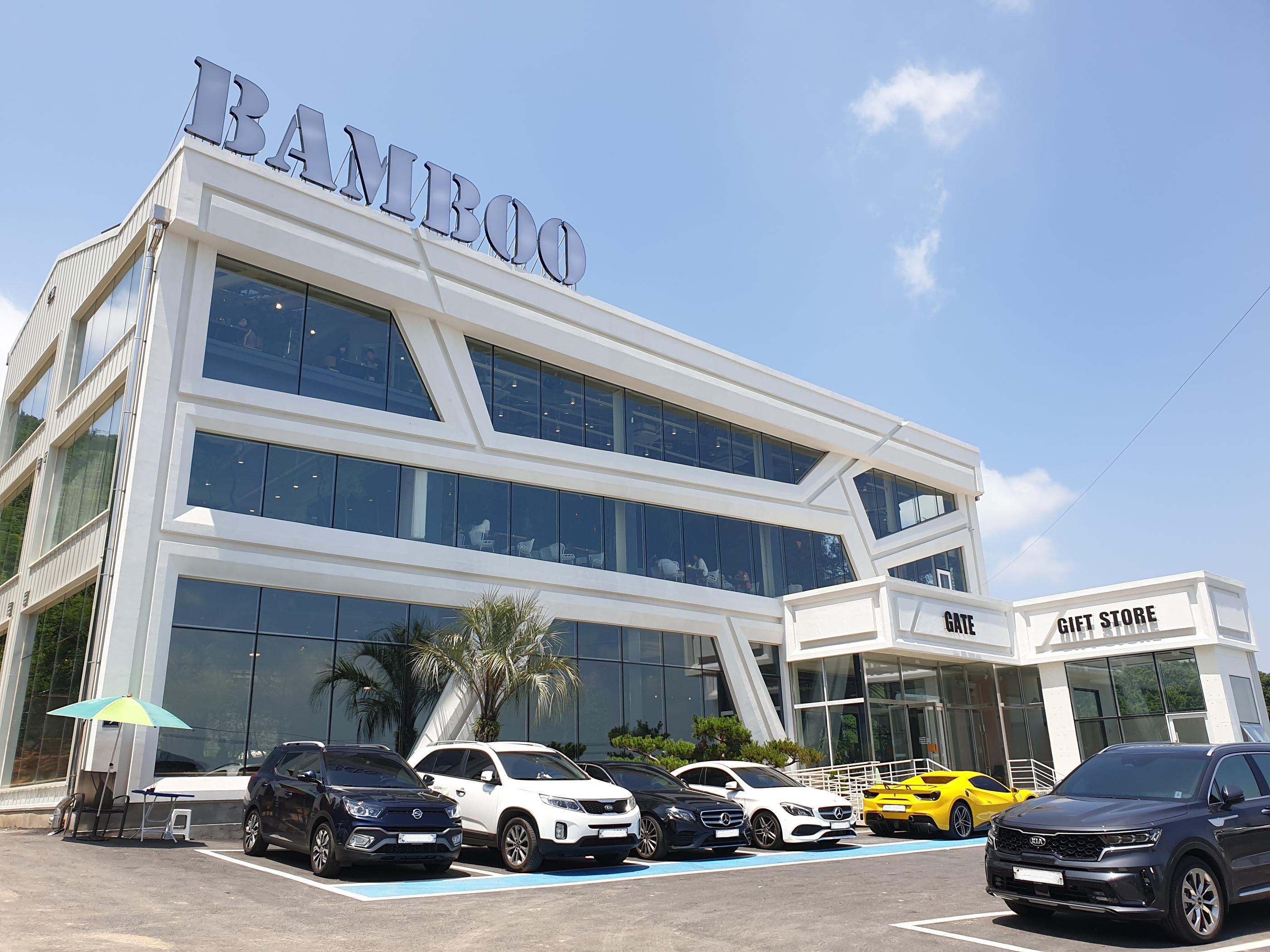 青空の下にある金浦の竹カフェBAMBOO15-8の外観。白い建物と駐車されている車が見えます。