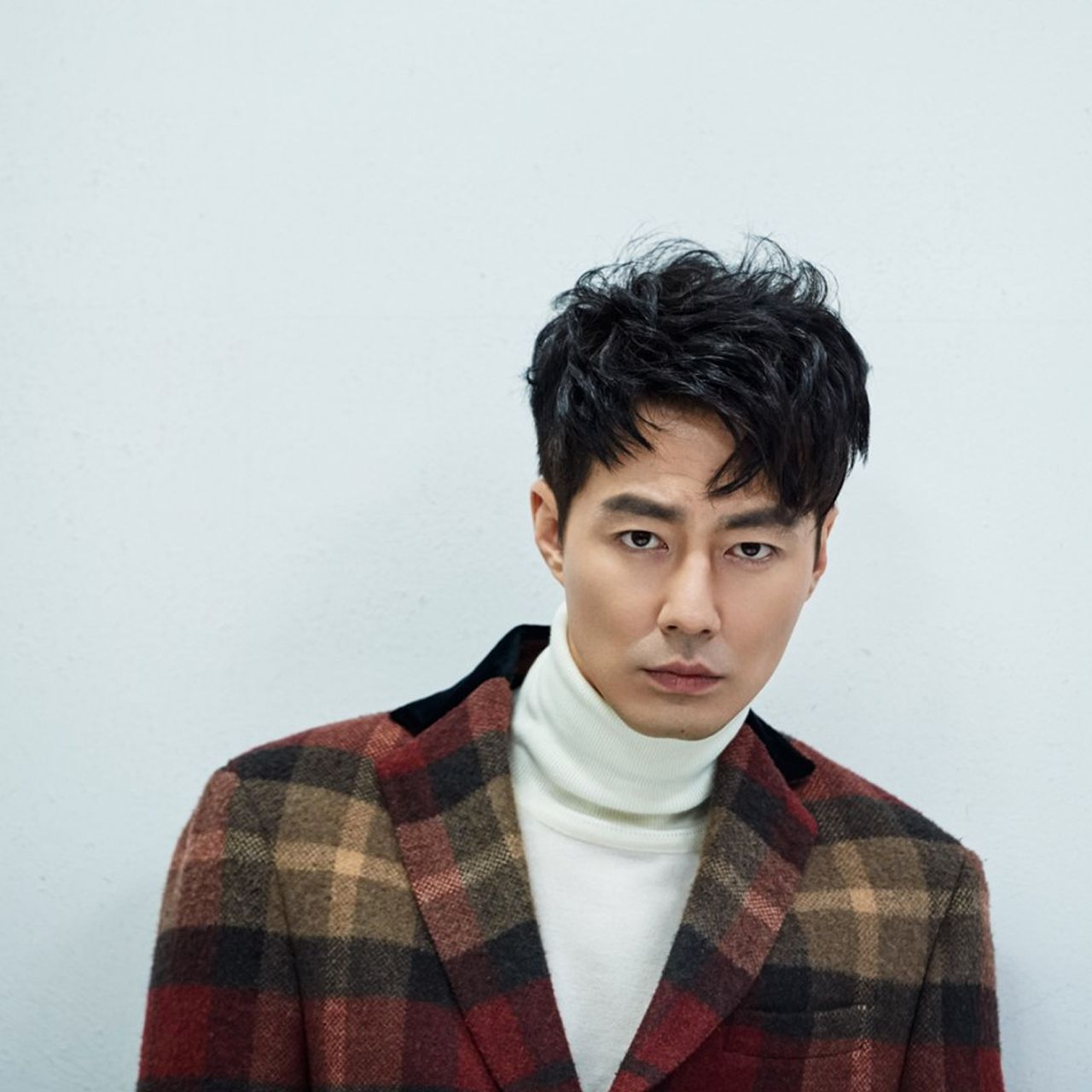 韩国演员赵寅成穿着有格纹设计的西装外套，搭配鲜明颜色的衬衫，展现出独特的时尚品味。