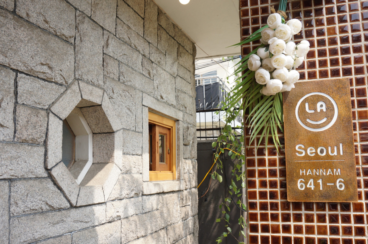 LALA BREADハンナム店の入口を示す石造りの壁の画像。「LA Seoul 641-6」のサインと花の装飾が見えます。