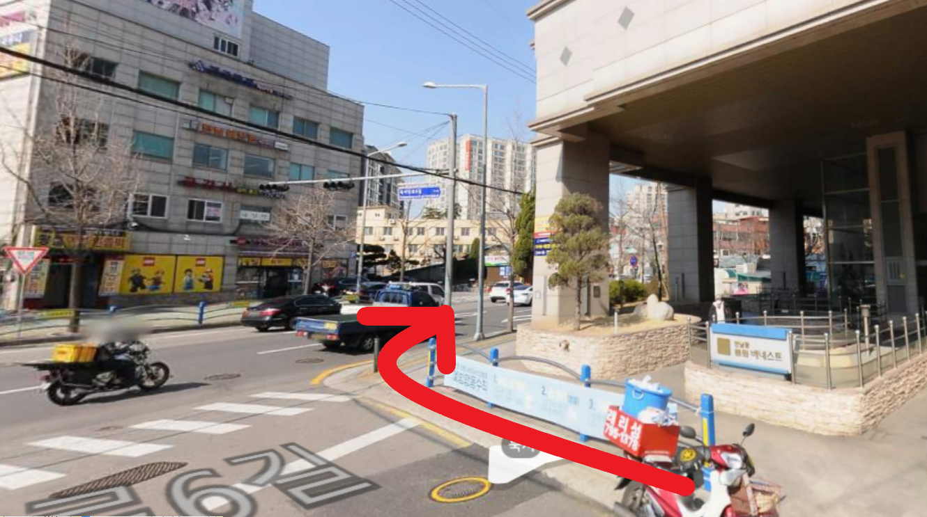 大きな通りにある交差点で右に曲がる道順を示す画像。道路に沿って走る車と赤い矢印が示されています。