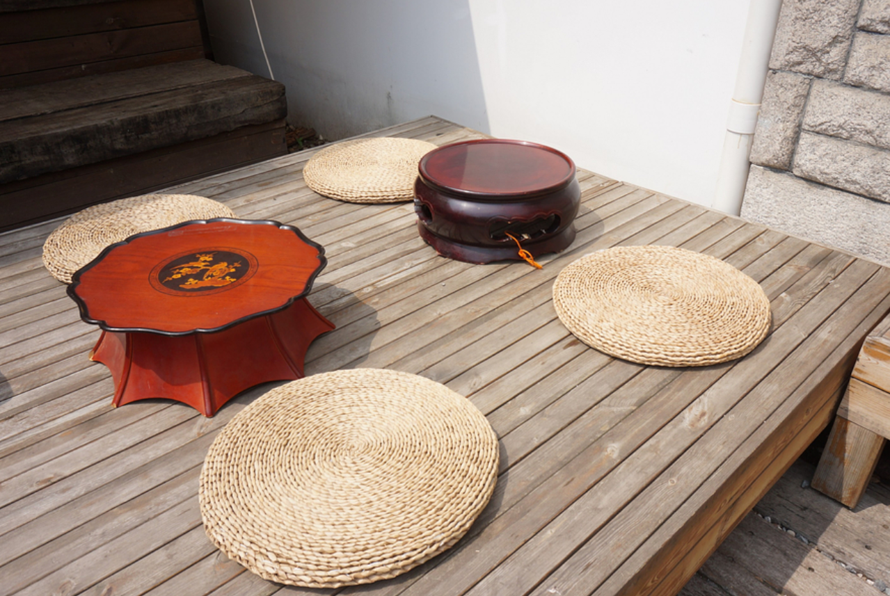 LALA BREADハンナム店のウッドデッキに配置された伝統的な韓国の丸テーブルと座布団。