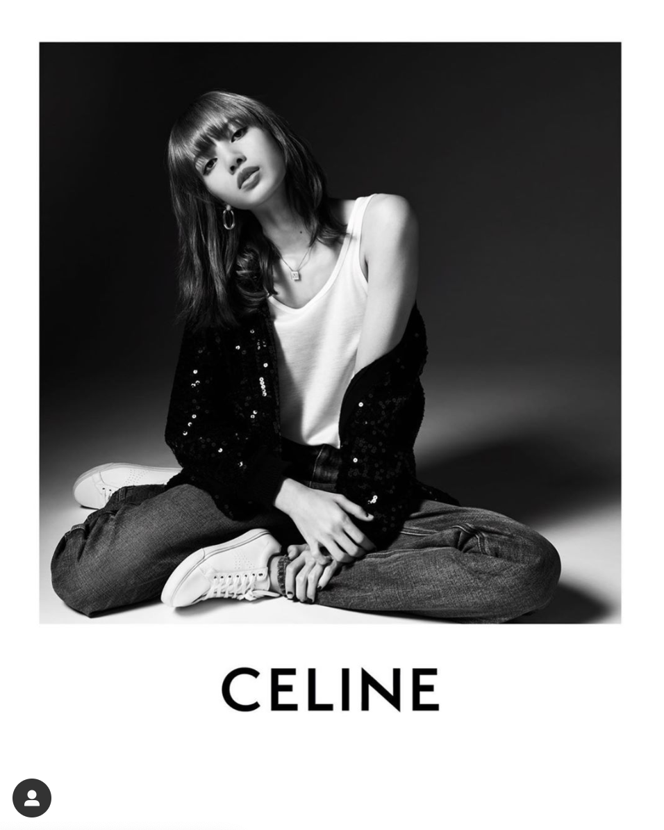 Foto en blanco y negro de una modelo vistiendo ropa de Celine, sentada en el suelo con piernas cruzadas, con una camiseta sin mangas y una chaqueta brillante