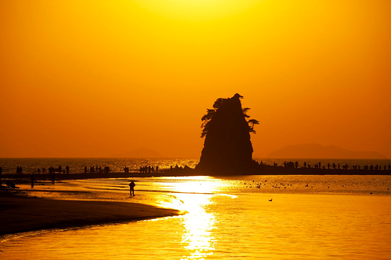 美麗的黃昏海灘，濃烈的黃色日落如畫，前景是海岸剪影。