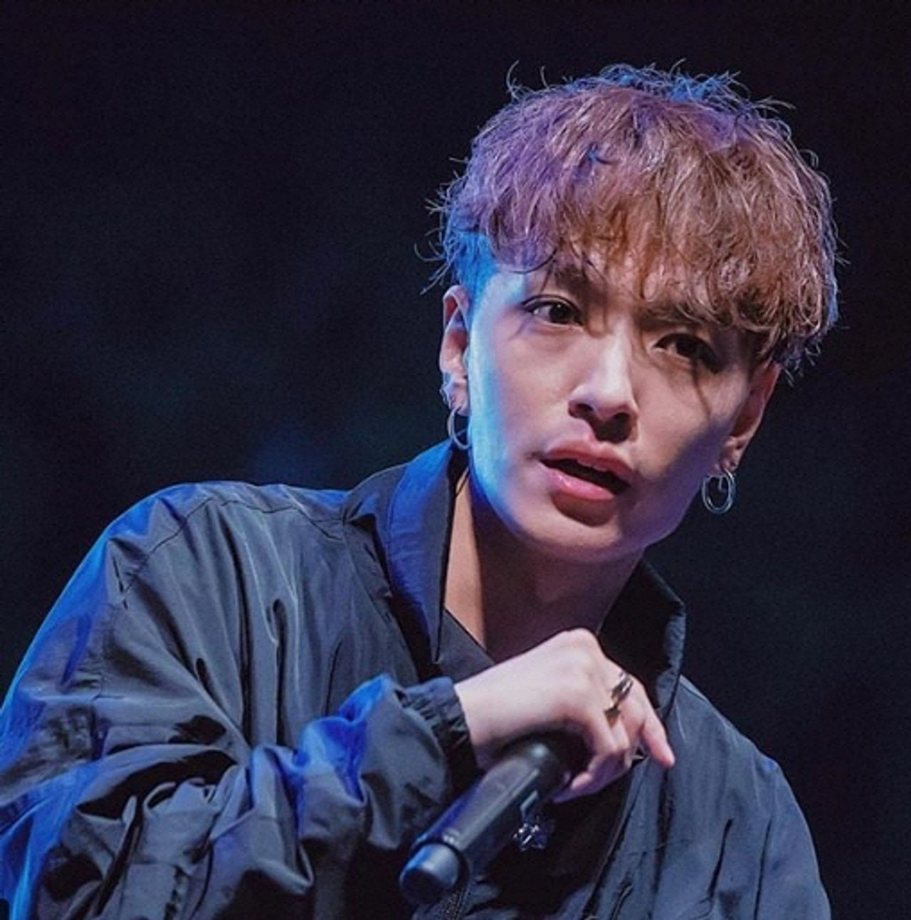 一名錶演者在聚光燈下，背景是黑暗的舞臺。