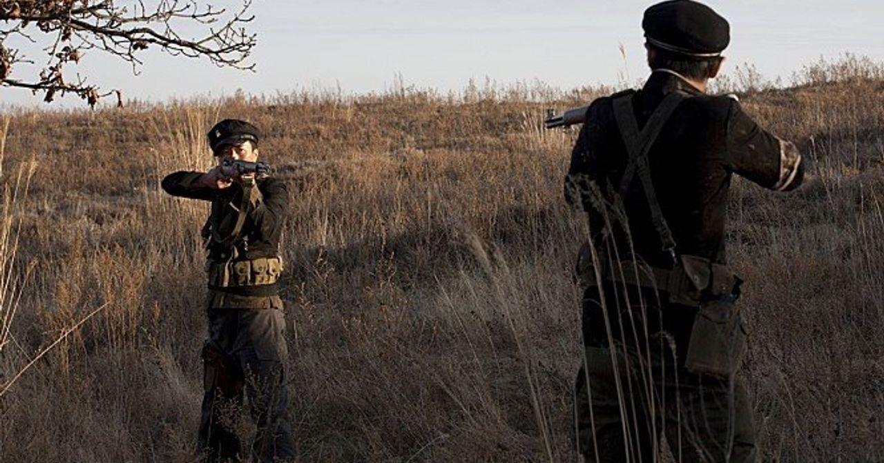 หนึ่งในบรรยากาศของช่วงสงครามเกาหลีที่ทหารกำลังถือปืนและเล็งเป้าหมายในการต่อสู้ในพื้นที่ธรรมชาติที่ดูแห้งแล้งและมีต้นไม้อยู่โดยรอบ