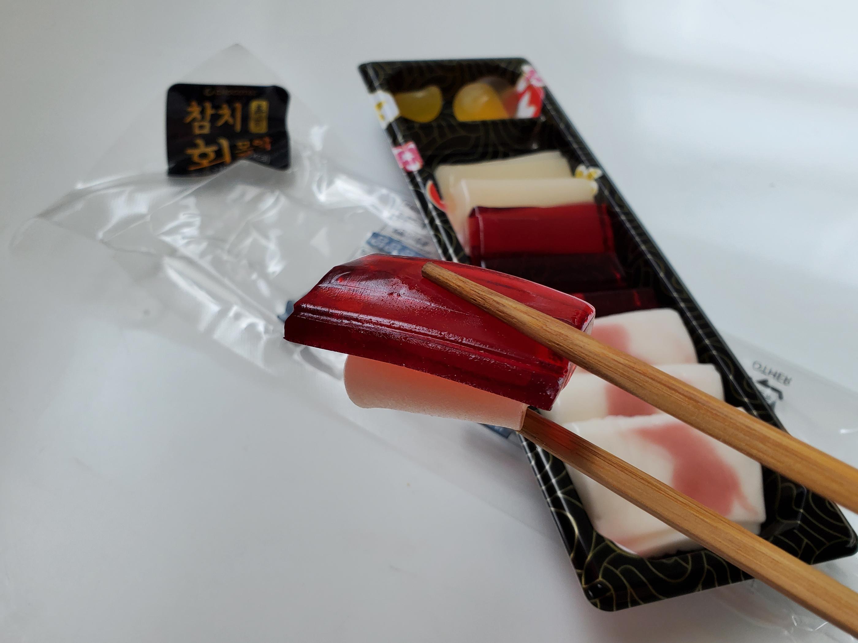 使用筷子夾取的韓國吞拿魚生壽司軟糖，近看可以看到柔軟的果凍質感。