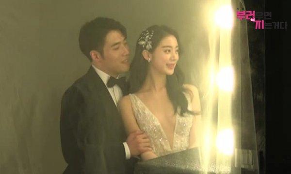 ウ・ヘリムとシン・ミンチョル、スタジオでのウェディング写真、ウ・ヘリムは華やかなドレスを着ており、シン・ミンチョルが後ろから優しく抱いている。