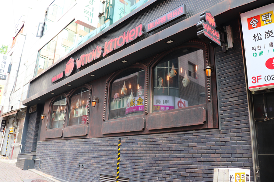 圖為新村的女巫廚房外觀,展示了其奇異的設計和平滑的磚牆。