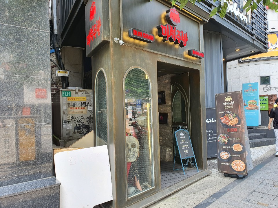 入口旁有骷髏裝飾的女巫廚房，給人一種神秘與奇幻的感覺，背景是都市街景