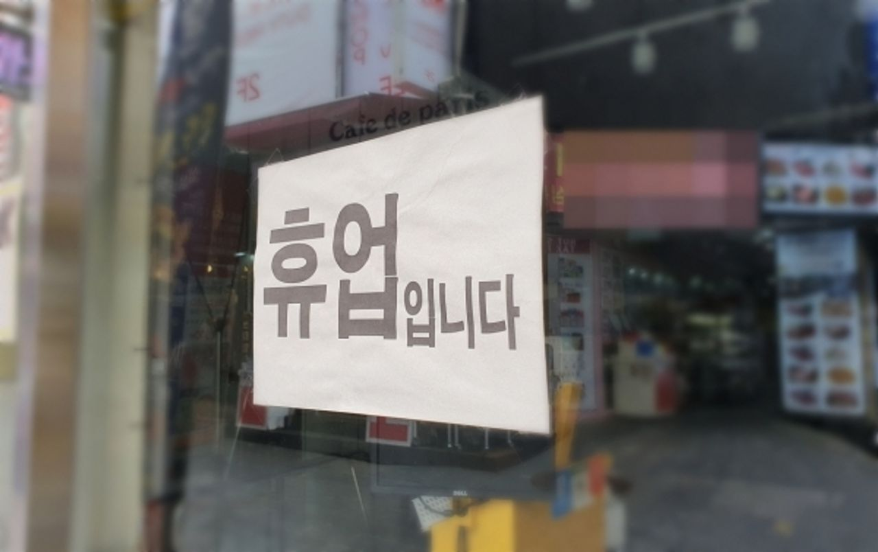 店铺窗户上贴有关于营业暂停的告示，反映出疫情对店铺运营的影响。