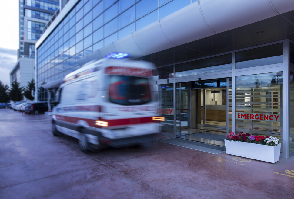 一輛救護車正在快速駛入醫院急診室，象徵著緊急情況及救援的緊迫性。