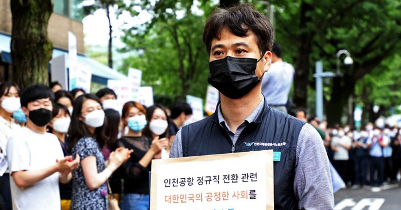 仁川机场工会成员在示威集会上举着标语，反映免税店工作人员对现状的不满。