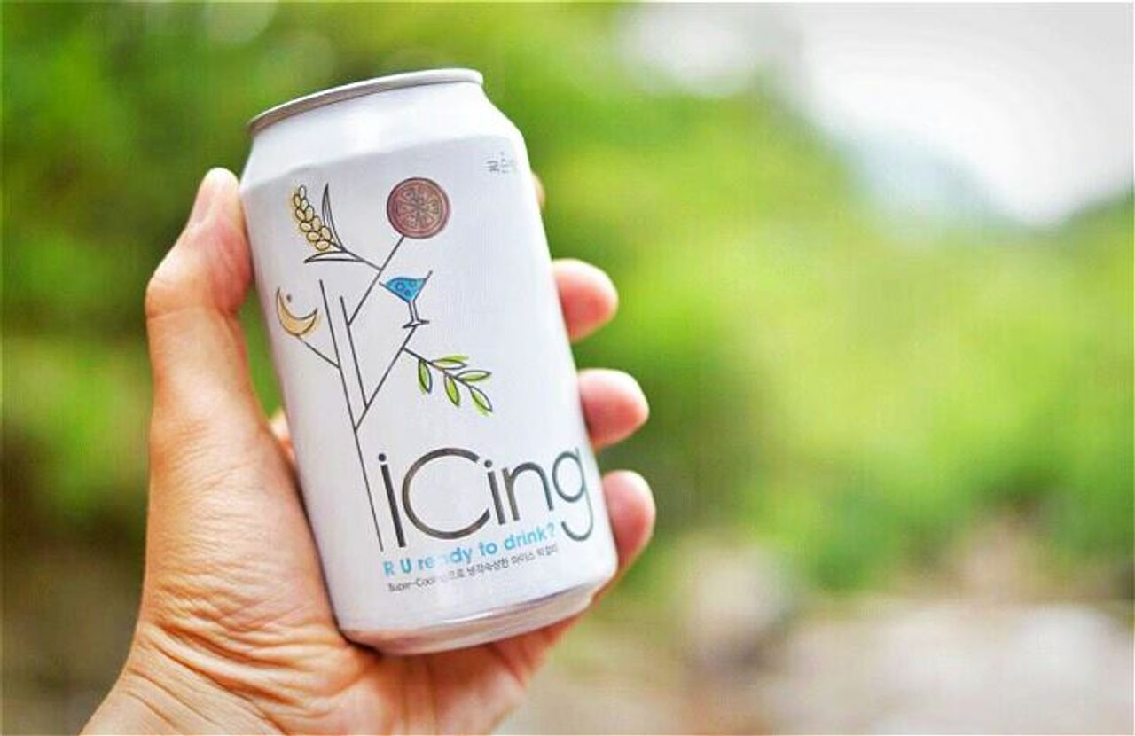戶外拍攝的 iCing 白色啤酒罐，帶有可愛插圖，令人耳目一新。