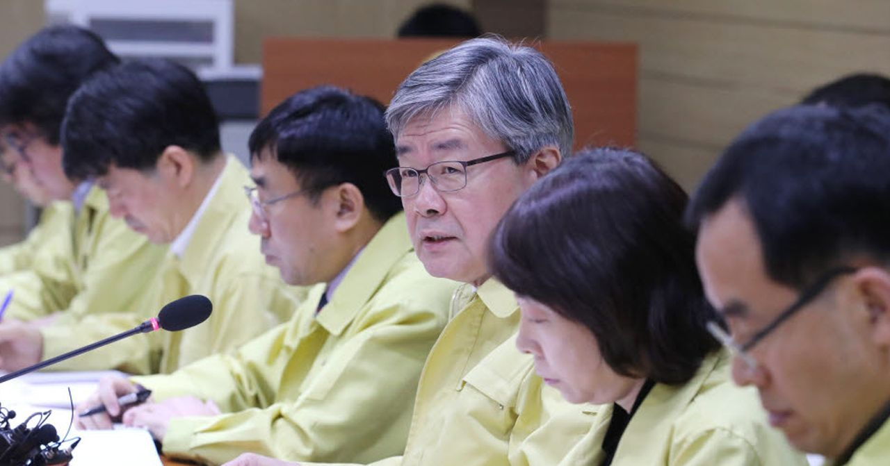 一群政府官員坐在會議室內商討政策，他們都穿著相同的黃色外套，象徵著韓國政府高層的危機應變措施。