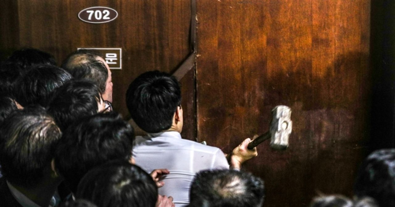 眾多議員集結在韓國國會大廳外，準備撞開阻擋的大門，場面激烈，展現出了政治僵局下的衝突情況。