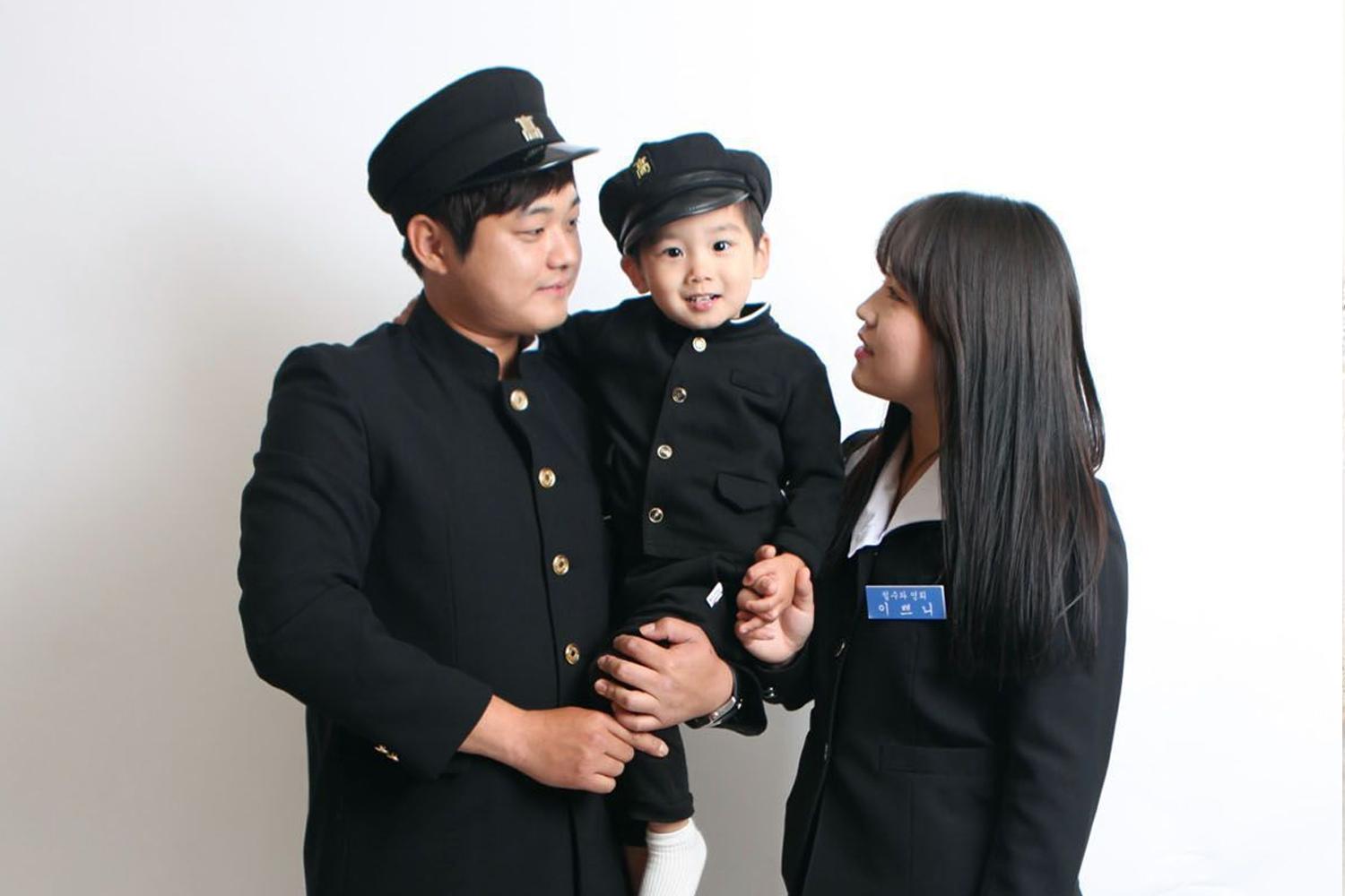 一家穿著舊式韓國校服的三口之家合影，充滿復古氣息。