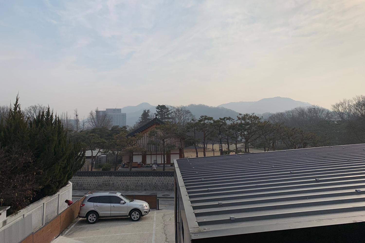 從韓屋內望向窗外，可以看到遠處的山景與城市景觀。