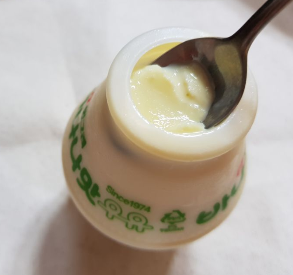 スプーンを使って凍ったバナナウユをすくっている様子。滑らかなクリーム状でアイスクリームのような食感を楽しめる。韓国で人気の冷凍食品。