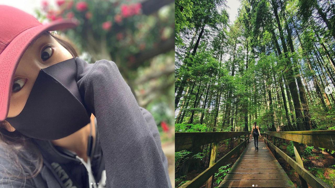 G.NA-ийн Instagram нийтлэлийн зураг, түүний хайртай хүмүүсээ анхаарсан сэтгэгдэл нь харагдах бөгөөд байгалийн орчинд алхаж буй хүний дүрс.