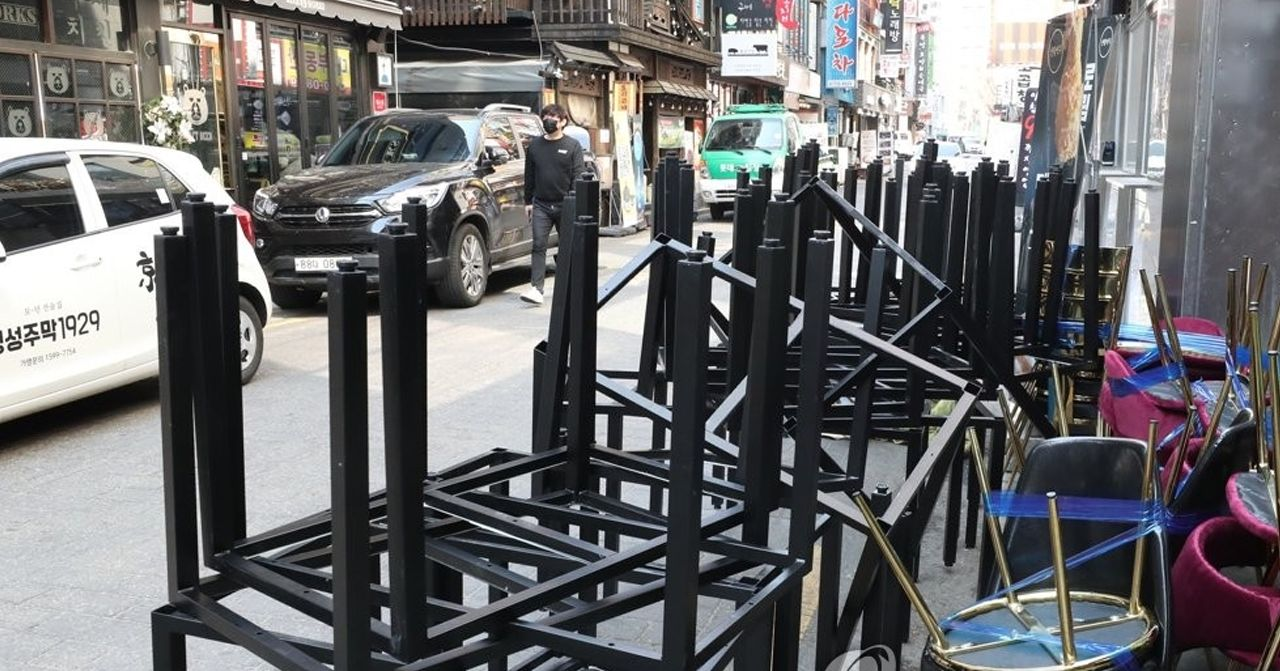 韓國街頭的餐廳外面堆放著沒有使用的椅子，顯示出新冠疫情對餐飲業的影響。